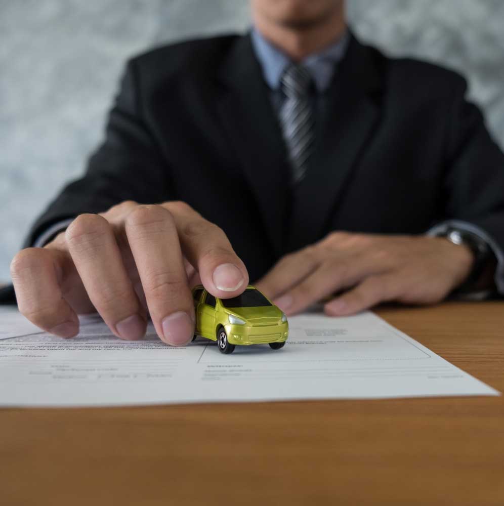 Appraisal Clause Auto Insurance concept showing an insurance professional reviewing a vehicle claim with a small car model placed on documents, representing auto insurance appraisal and claim evaluation process.