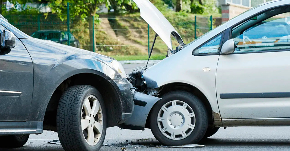 Front-end car collision with two vehicles bumper-to-bumper and visible damage on a city street, representing insurance assessment and Diminished Value Claim Hawaii after an accident.