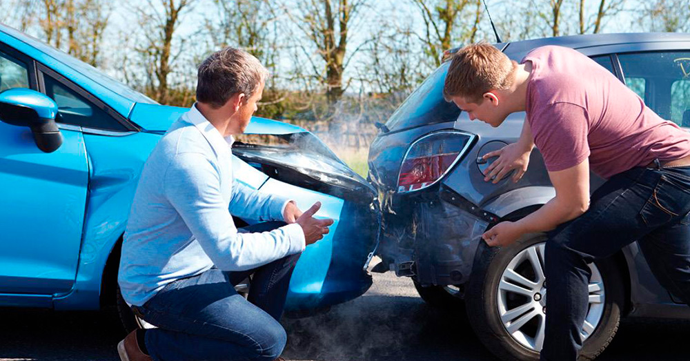 Rear-end car accident with two drivers inspecting bumper damage and smoke between vehicles on a roadside, showing insurance inspection and Diminished Value Claim Montana after a collision.