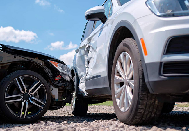 Side-impact car accident with visible door damage between two vehicles on a gravel surface, illustrating insurance evaluation and Diminished Value Claim North Carolina after an auto collision