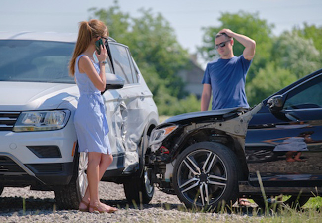 Two drivers at a collision scene inspecting side-impact damage between an SUV and a sedan while making phone calls, illustrating insurance evaluation and Diminished Value Claim North Carolina after a car accident