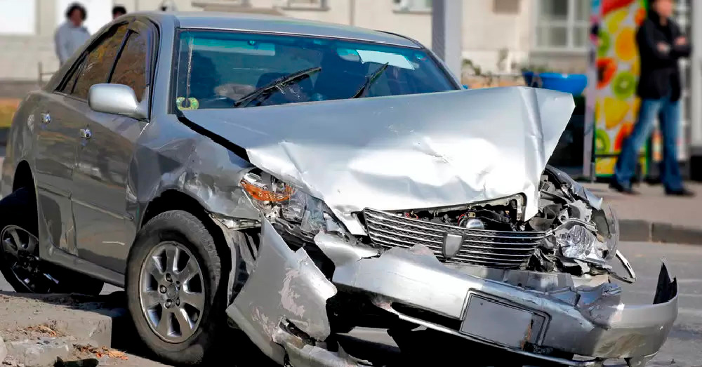 Severely damaged sedan with crushed front end after an urban collision, showing insurance inspection and Montana Total Loss Threshold following a serious auto accident