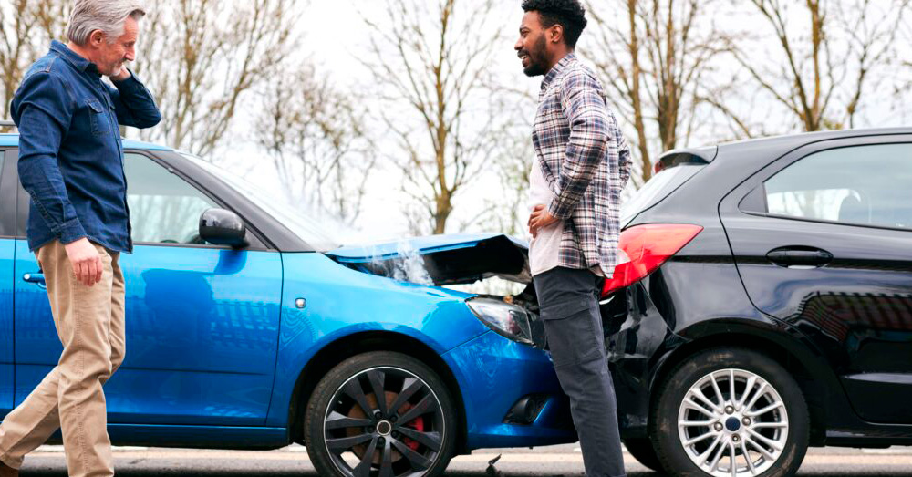Two drivers discussing a rear-end car accident with visible bumper damage between vehicles, illustrating insurance evaluation and New York Total Loss Threshold after an auto collision