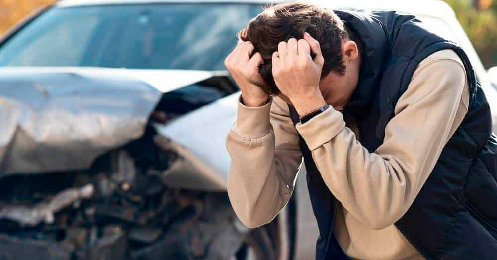 Distressed driver holding his head beside a severely damaged vehicle after a collision, illustrating insurance evaluation and Diminished Value Claim Oregon following a serious auto accident